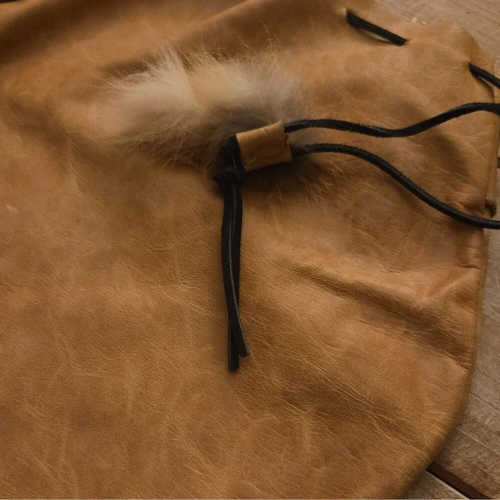 Handcrafted tan leather drawstring pouch featuring a soft fur pom-pom